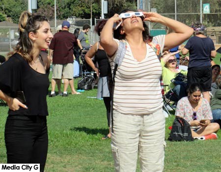 Photo: FLLewis / Media City G -- Woman takes her turn looking through eclipse glasses at the wonder of nature in the sky Burbank August 21, 2017